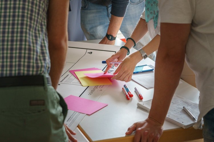 Menschen stehen um einen Tisch und machen ein Brainstorming